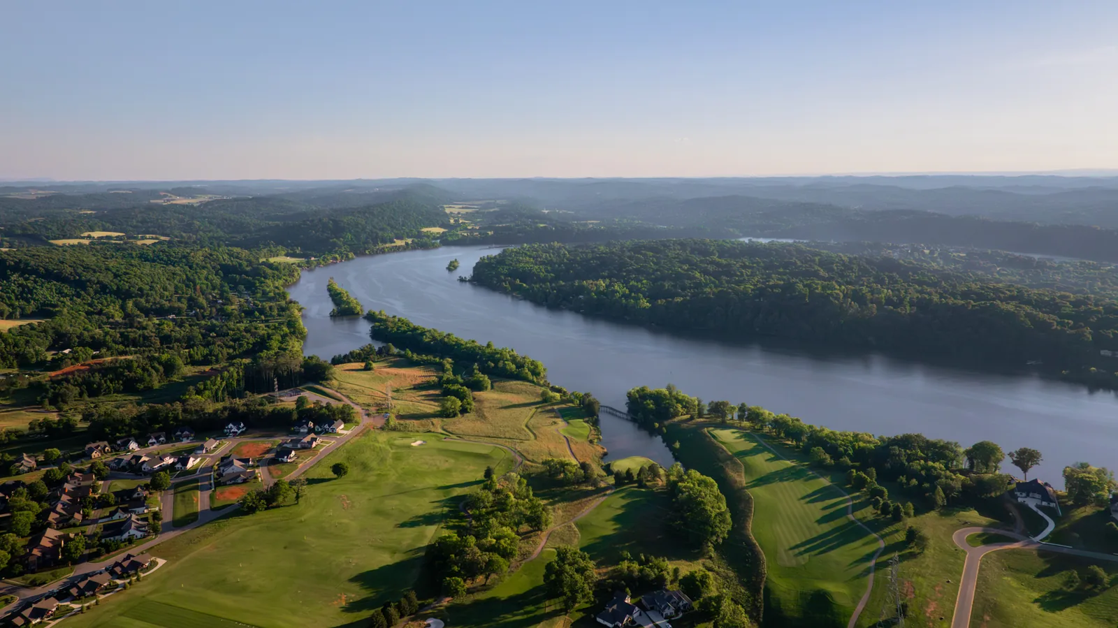 Aerial view of Tennessee National on Watts Bar Lake — Greg Norman golf course, marina and gated lakefront community at sunrise